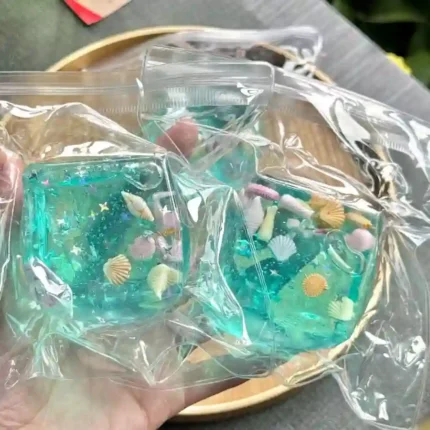 Transparent Ocean Ice Cube Squishy Stress Toy with colourful sea life decorations, supplied in a reusable zip-lock pouch. Slow-rising sensory fidget toy available from SDMAX Toys Wholesaler UK.