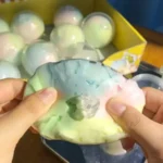 Rainbow Colour Crispy Ball Squishy slow-rise stress balls in assorted colours displayed in a 12-piece retail counter display box by SDMAX Toys Wholesaler.