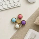 Sensory Dumpling Spinner Fidget Toy with four colourful silicone dumpling buttons inside miniature bamboo steamer baskets and central spinner by SDMAX Toys Wholesaler.