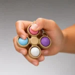 Sensory Dumpling Spinner Fidget Toy with four colourful silicone dumpling buttons inside miniature bamboo steamer baskets and central spinner by SDMAX Toys Wholesaler.