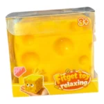 Crunchy yellow cheese block squishy toy with rounded cheese holes, shown in hand and in individual retail packaging with a 12-piece display box, approximately 7 × 7 cm, from SDMAX Toys Wholesaler.