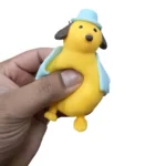 Cute Pet Puppy Squishy Toy featuring a yellow puppy with brown floppy ears, blue hat and blue outfit, individual packaging and wholesale display box, 10 × 6cm, £2.85 each – SDMAX Toys Wholesaler.